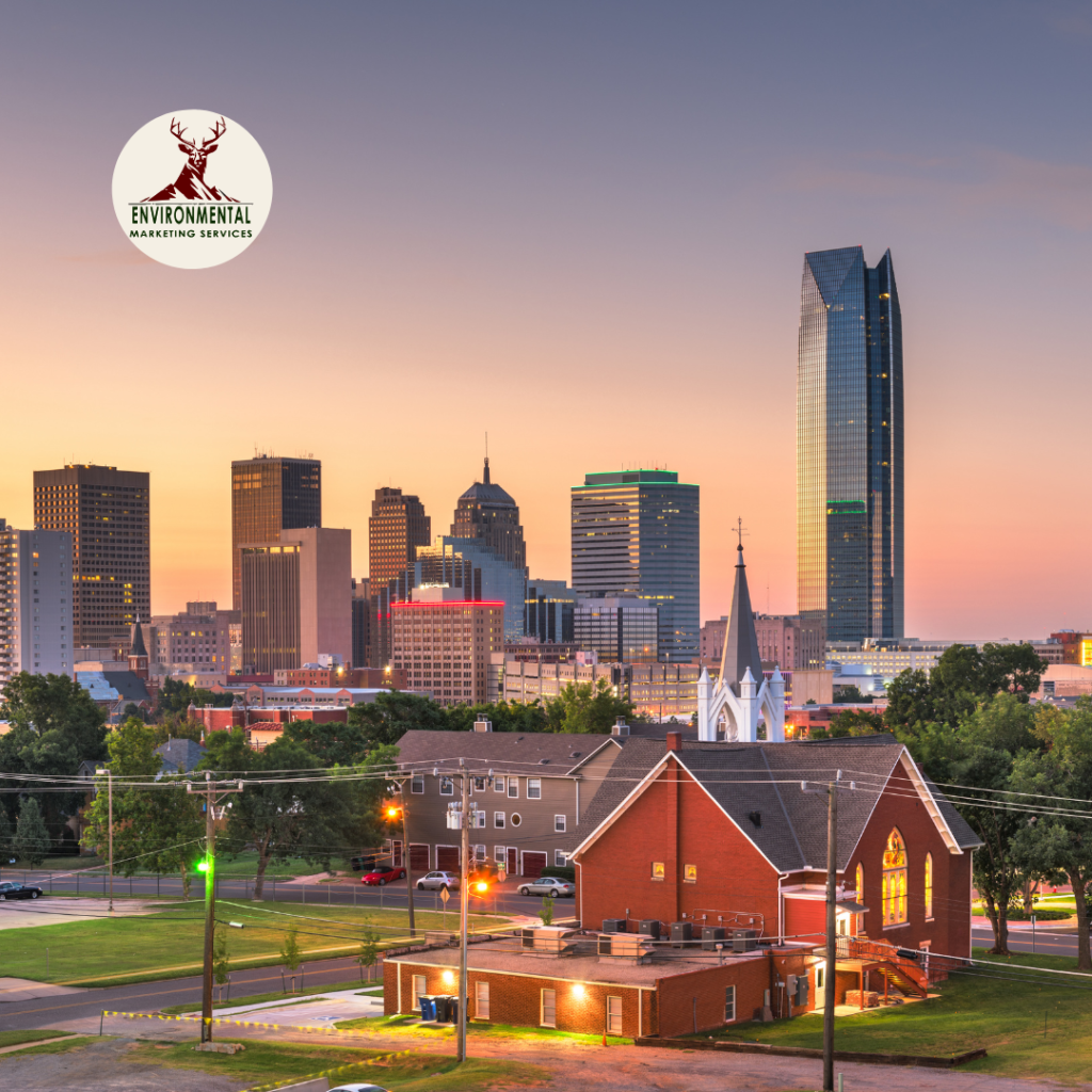 A cityscape of Oklahoma City at dusk featuring the Devon Energy Center skyline, a red brick church in the foreground